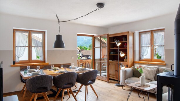 A dining area with a wooden table and chairs, a sofa, and a television. - Apartment 'Ferienwohnung Regina' with Mountain View, Balcony and Wi-Fi (Mittenwald)
