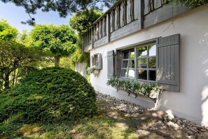 Un bâtiment à l’extérieur blanc, doté de volets en bois et d’un chemin de pierre menant à l’entrée.