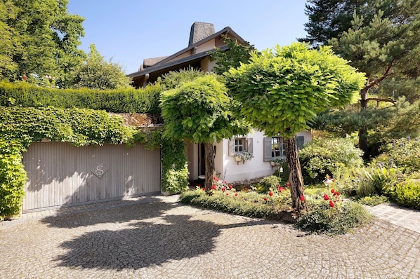 Une maison avec une allée pavée, une clôture en bois et un jardin agrémenté de fleurs rouges.