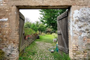 Ein Gartenbereich mit einem Kopfsteinpflasterweg, Holztoren und Blumentöpfen.