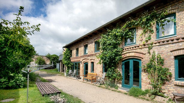 A brick building with a garden, outdoor seating, and a gravel path. - Finca 'Gruppenhaus' with Shared Terrace, Communal Garden and Wi-Fi (Groß Kreutz (Havel))