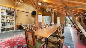 A spacious room with a long wooden table, chairs, a bookshelf, and a large window. - Finca 'Gruppenhaus' with Shared Terrace, Communal Garden and Wi-Fi (Groß Kreutz (Havel))