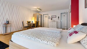 Une chambre à coucher comprenant un lit, un bureau, une chaise, une armoire et un mur d’accent de couleur rouge.