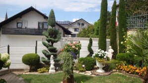 Un jardin résidentiel avec des pelouses parfaitement entretenues, diverses sculptures en topiaire et une clôture blanche.