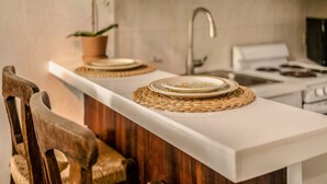 A kitchen with a white countertop, a wooden chair, a potted plant, and a stove. - Ocean Breeze | Old San Juan | Spanish Style (San Juan)