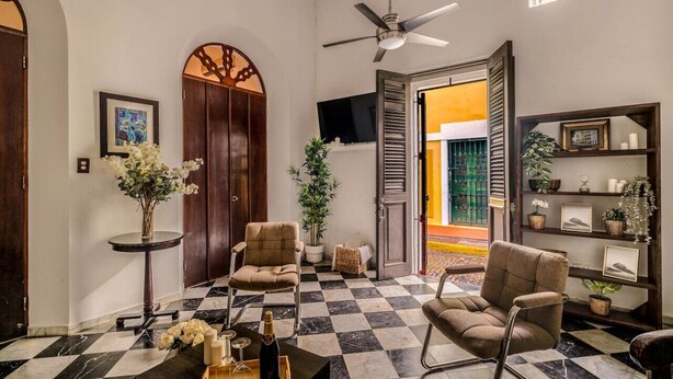 A spacious living room with a checkered floor, a ceiling fan, and a view of the outside. - Ocean Breeze | Old San Juan | Spanish Style (San Juan)