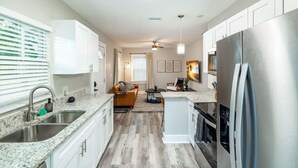 A modern kitchen with white cabinets, stainless steel appliances, and a granite countertop.