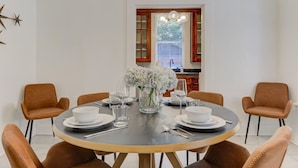 A dining area with a round table set for four, surrounded by brown upholstered chairs. - The Cooper Suite | Midtown Memphis (Memphis)