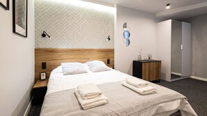 A modern hotel room with a neatly made bed, a wooden headboard, and a small bedside table with a lamp. - Estrella 7 Elegancki Apartament W Sercu Torunia (Torun)