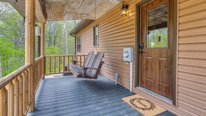A wooden porch with a swing chair and a door with a window. - Family-Friendly Milton Home on 14 Acres w/ Hot Tub (Milton)