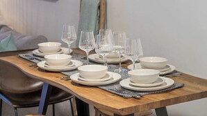 A dining table set with white bowls and wine glasses, a wooden table, and a black and white placemat.