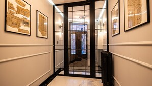 A hallway with framed historical documents on the walls, a marble floor, and a black-framed door leading to another room. - Estrella 4 Ekskluzywny Pobyt Blisko Restauracji i Kawiarni (Torun)