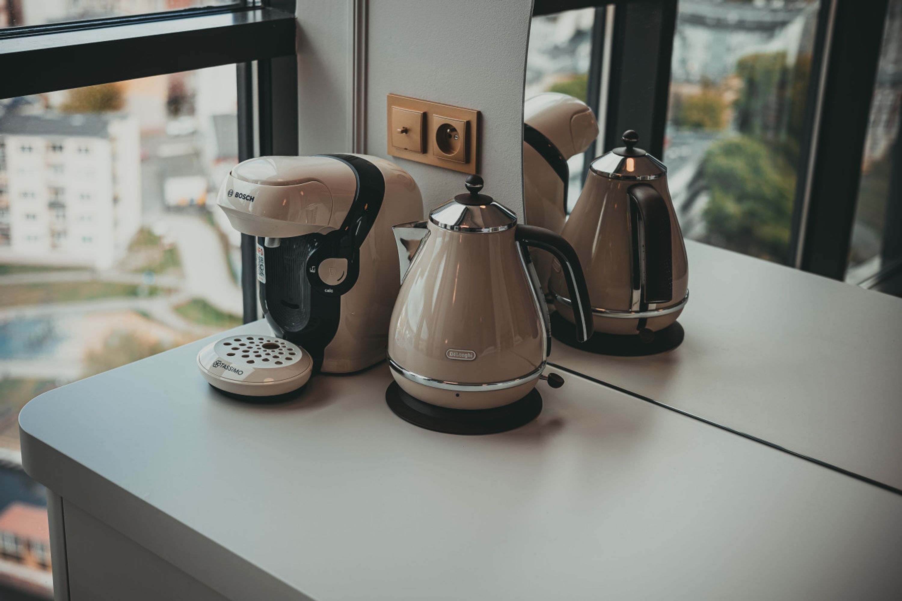 Una kitchenette con cafetera, hervidor y un electrodoméstico Bosch sobre una encimera.