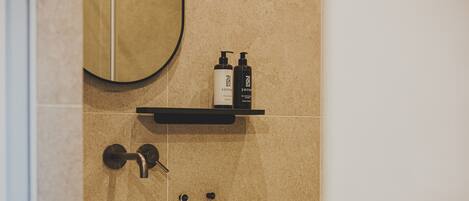 A bathroom with a white sink, a towel hanging on a rack, and two bottles on a shelf above the sink.