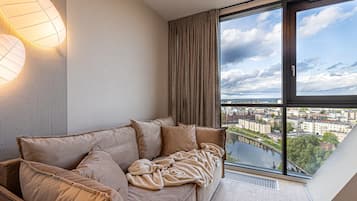 Ein modernes Wohnzimmer mit großem Fenster, einer Couch und einer Wandleuchte.