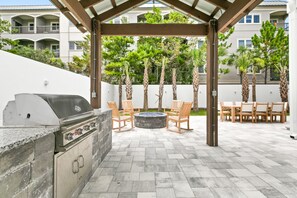 An outdoor patio with a grill, seating, and a fire pit.