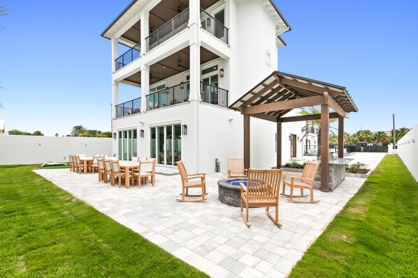 A two-story building with a covered patio area featuring outdoor furniture and a fire pit.