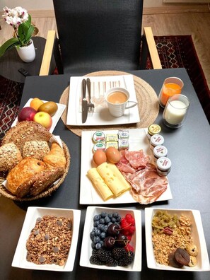 A breakfast table with various food items including bread, cheese, meats, fruits, and beverages. - Royas Home Private Studio (Zaventem)