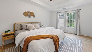 Ein Schlafzimmer mit Bett, Nachttisch, Deckenventilator und Blick ins Freie durch ein Fenster.