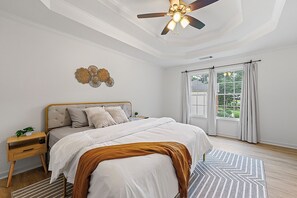 A bedroom with a bed, nightstand, ceiling fan, and a view of the outdoors through a window. - 🌟 MODERN 5-BEDROOM🛏️, PERFECT FOR LARGE FAMILIES! SPACIOUS SUNROOM ☀️ (Lawrenceville)