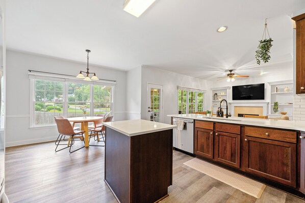 A spacious kitchen with a large island, wooden cabinets, and a built-in TV.