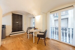 A dining area with a table and chairs, a dark door, and a balcony with a railing. - Genova Studio in San Lorenzo (Genoa)