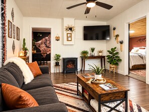 A living room with a sofa, coffee table, fireplace, and a television. - Firepit | off I-80 | Private Carport |1BR | Pets (Lyman)