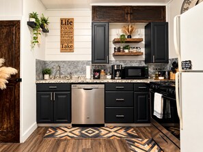 A modern kitchen with black cabinets, stainless steel appliances, and a decorative rug. - Firepit | off I-80 | Private Carport |1BR | Pets (Lyman)