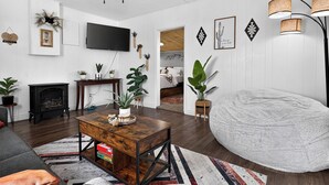 A modern living room with a fireplace, a large TV, and a bean bag chair.