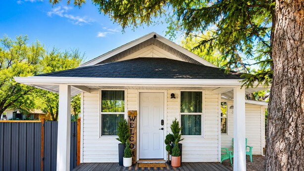 A single-story house with a front porch, a welcome sign, and a mailbox.