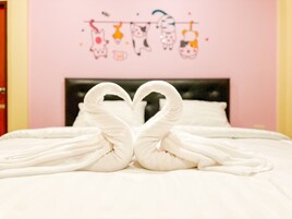 Un lit avec des serviettes blanches disposées en forme de cœur.