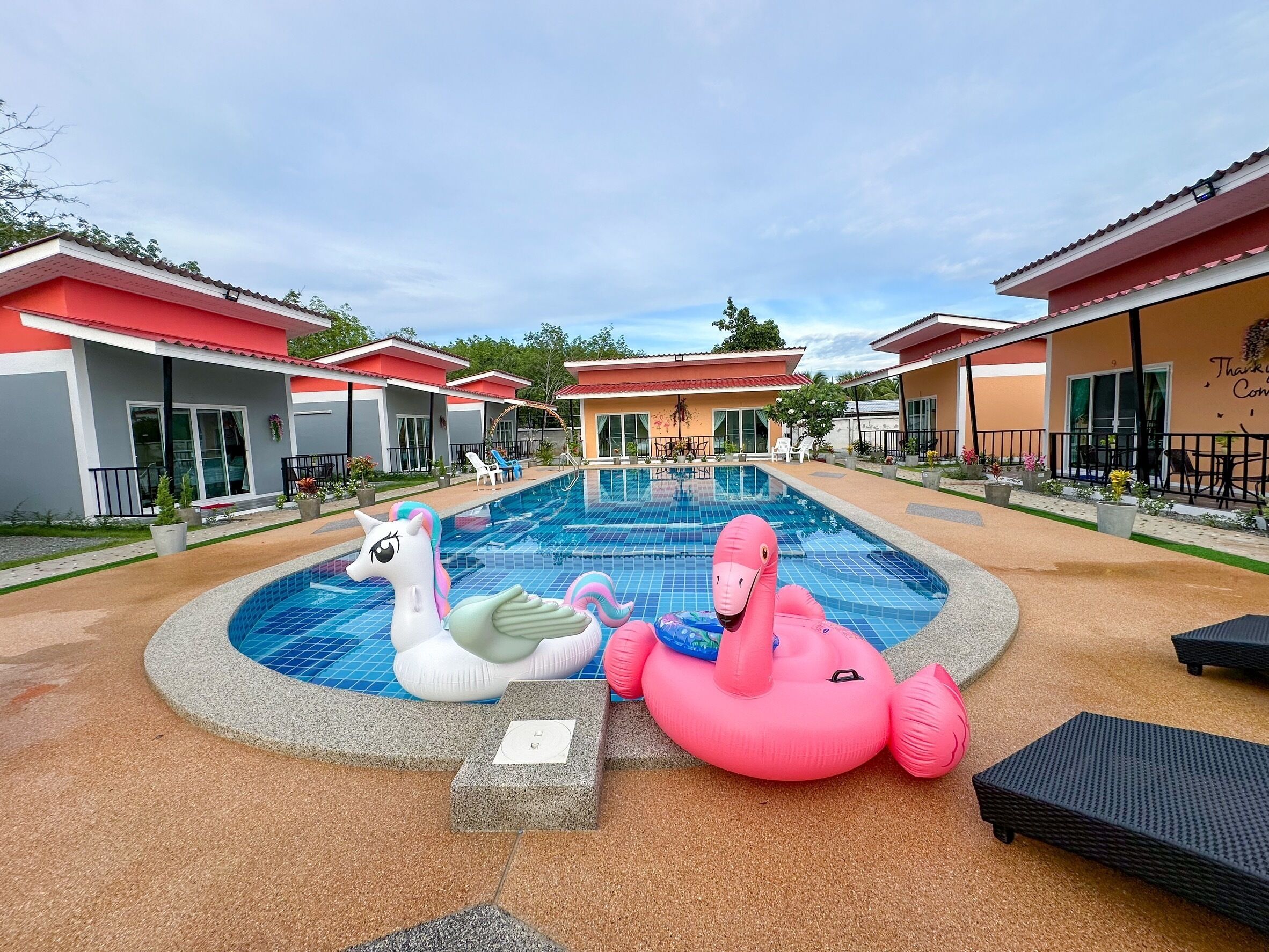 Een buitenzwembad, parasols bij het zwembad en ligstoelen