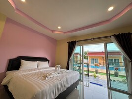 A hotel room with a large bed, a view of a swimming pool, and a balcony.