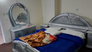 Quarto com cama, mesa de cabeceira, espelho e cômoda.