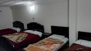 Quarto com três camas, cada uma com estilo diferente de cabeceira e roupa de cama.