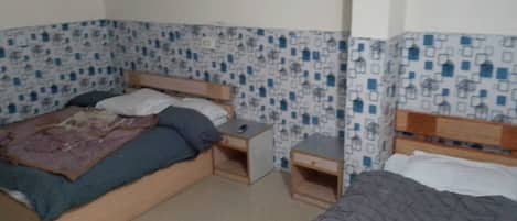 A small, simple room with a bed, a nightstand, and a dresser.