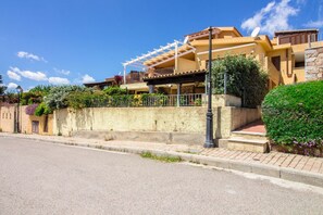 A two-story building with a balcony, a satellite dish, and a stone wall.