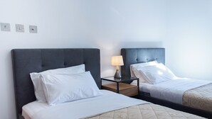 Ett hotellrum med två sängar, ett nattduksbord med en lampa och en väggmonterad ljusströmbrytare.