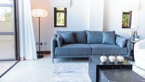 Ett modernt vardagsrum med en grå soffa, ett svart soffbord och en golvlampa.