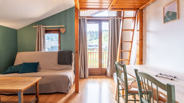 A cozy room with a bed, a table, and chairs, a balcony with a view of the outdoors. - Nice apt for 6 people near the slopes (Morillon)