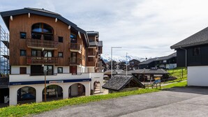 A multi-story hotel with balconies, a ski resort sign, and a mountain backdrop. - Nice apt for 6 people near the slopes (Morillon)