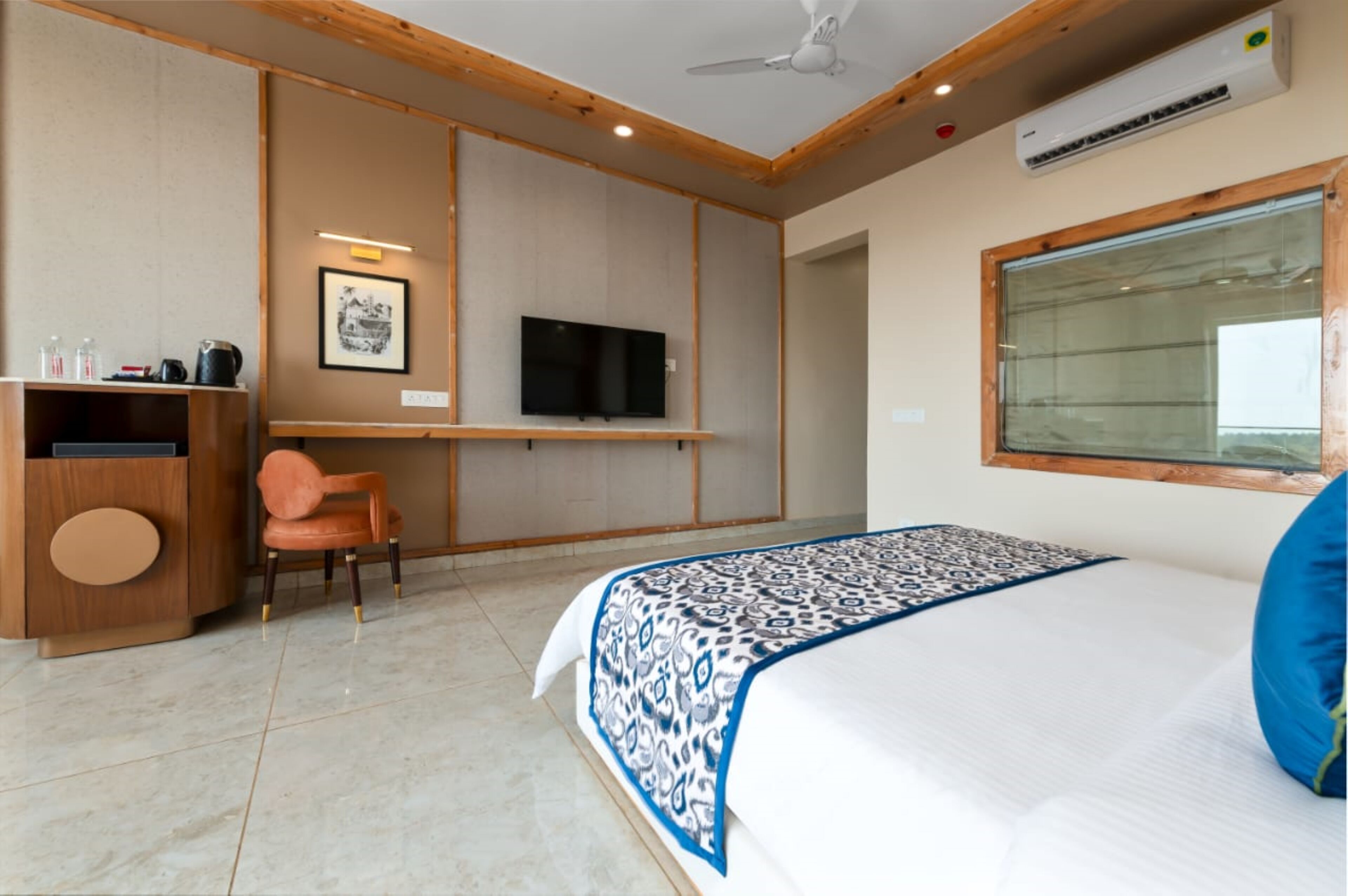 Quarto de hotel com cama, televisão, escrivaninha e cadeira.