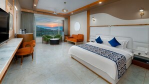 Una habitación de hotel moderna con una cama grande, un escritorio y vistas a las montañas.