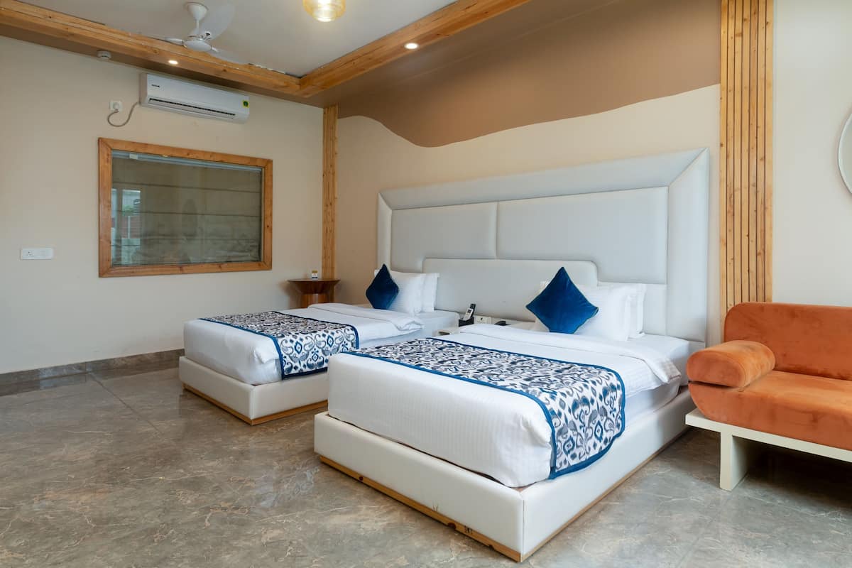 A hotel room with two beds, a wooden ceiling, a window, and a small table.