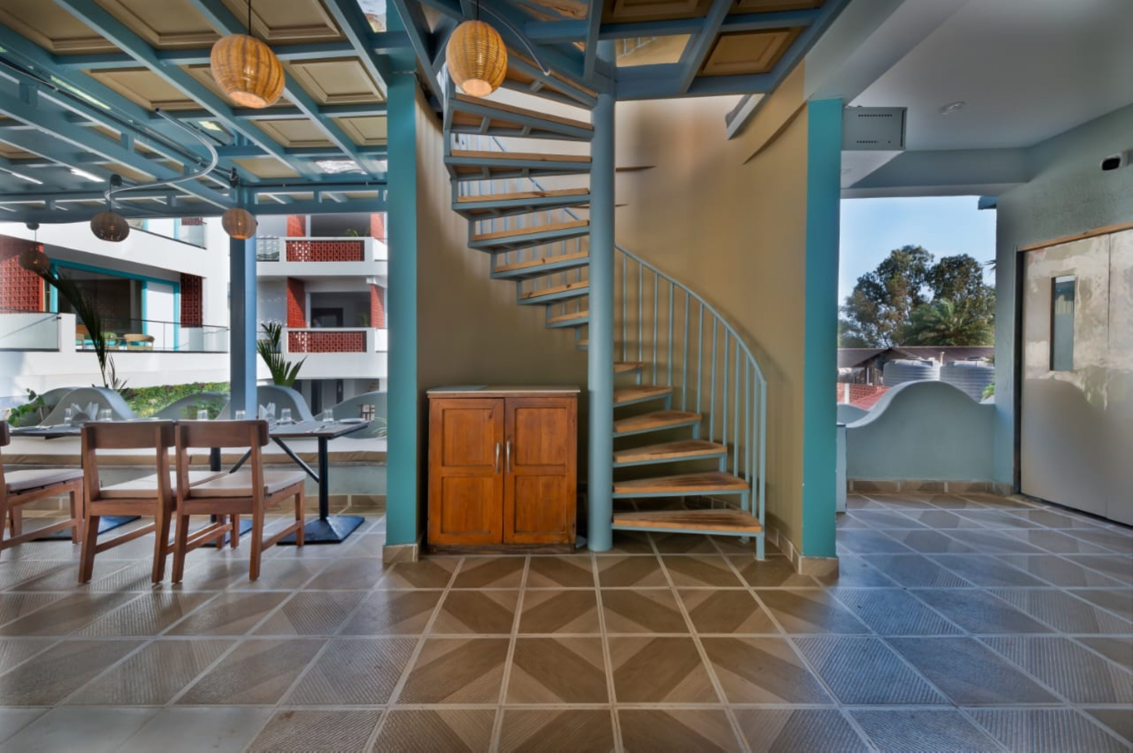 A spacious indoor area with a staircase, wooden furniture, and a tiled floor.