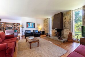 Een woonkamer met een open haard, een boekenkast en een rode bank.