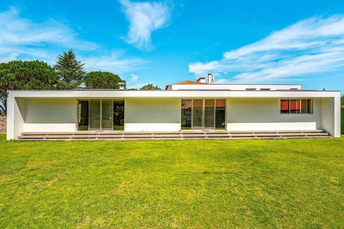 Un edificio moderno de una sola planta con tejado plano, ventanas amplias y un césped cuidado.