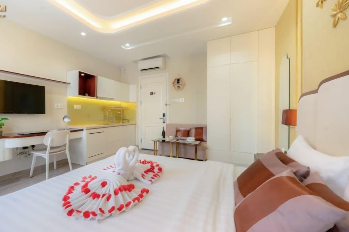 Une chambre d’hôtel équipée d’un lit, d’un bureau, d’une chaise, d’une télévision et d’une kitchenette.