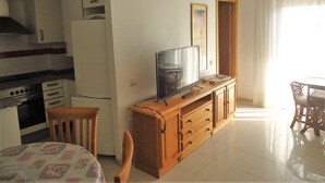A compact living space with a kitchenette, a dining area, and a TV on a wooden cabinet. - Orlando LEK (Benicarló)