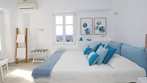 A bedroom with a large bed, a window with a view, a small table, and a chair. - Waterfront Villa Angelika Pink Pelikan (Mykonos)